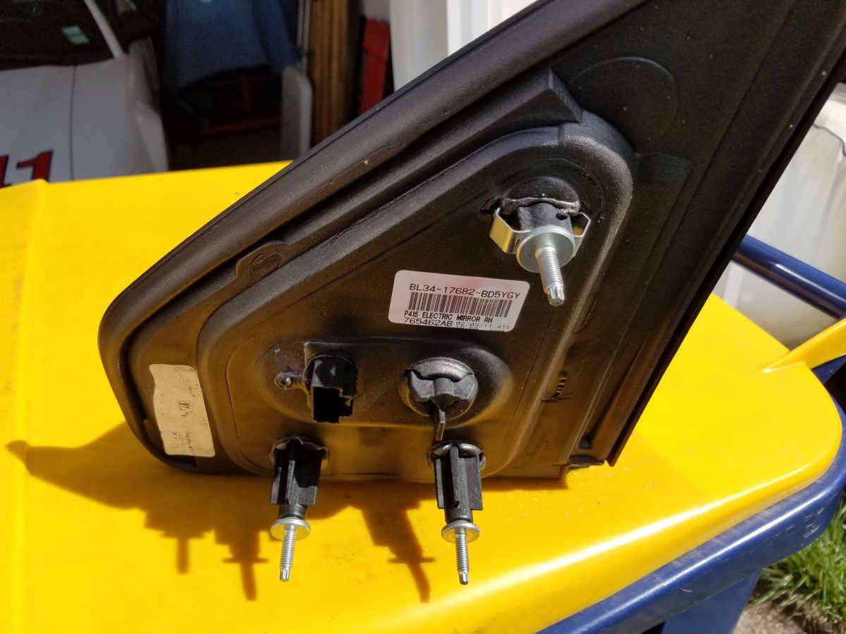This picture shows the new mirror waiting to go on. Note the top most stud also has the large keeper-spring to hold the mirror to the door even when all three nuts have been removed.