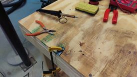 With the board held down, heat with the iron and pull with the pliers