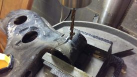 A drill press vise is handy, but you can use a hand drill